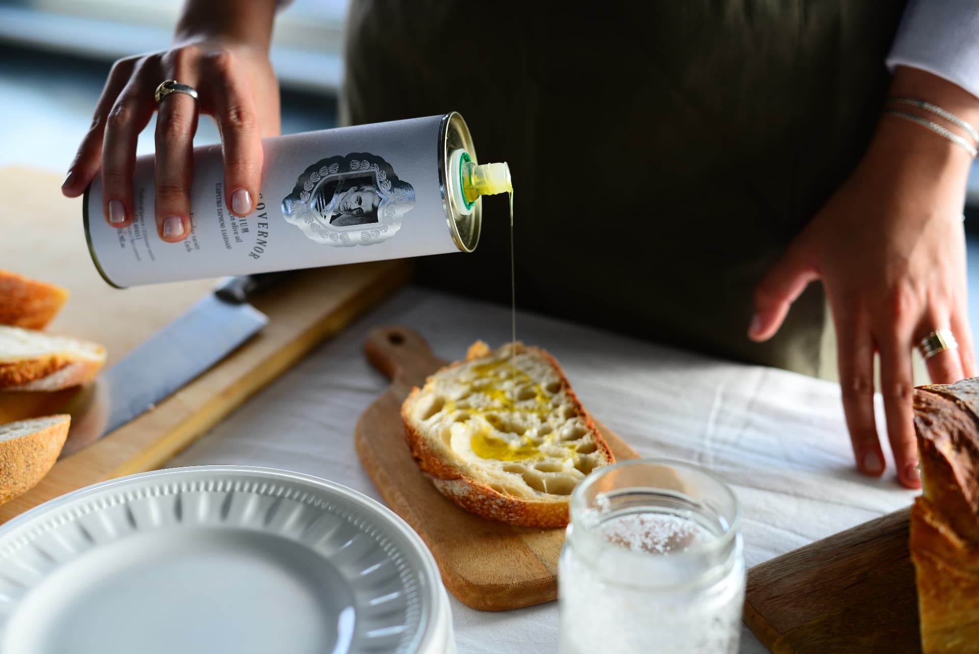 olive oil being poured over a slice of rustic bread on a wooden board