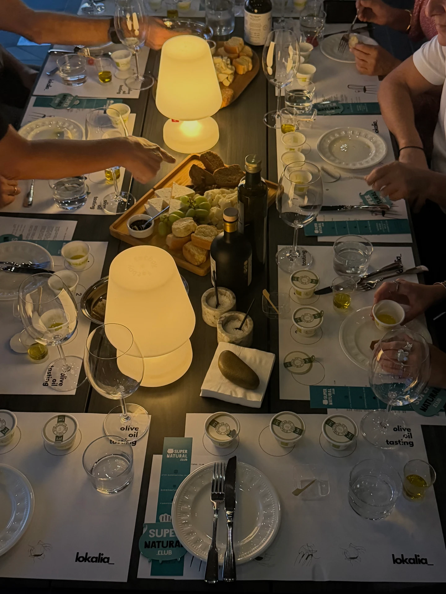 guests sharing Lemnian food and olive oil by lamplight