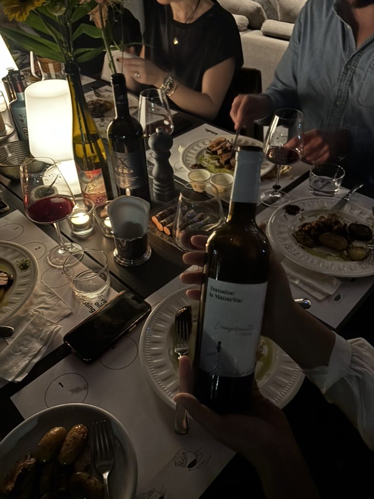 a bottle of wine open beside plates and candlelight