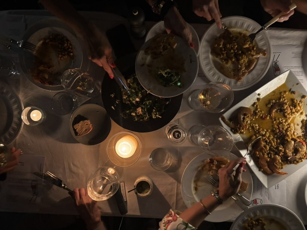 plates and candles mid-supper, hands reaching across the table